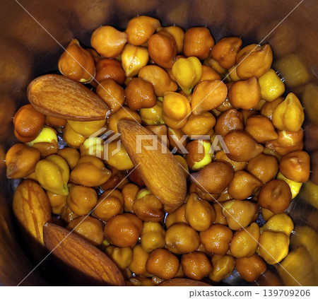 Close up view of soaked chickpeas and raw almonds in metal cup. 139709206