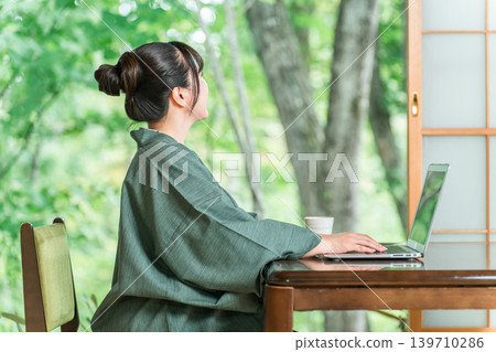 一位身穿浴衣的女子在溫泉旅館的房間使用電腦 139710286