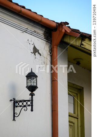Weathered house corner with lantern and gutter downspout Weathered house corner with lantern and gutter downspout 139710494