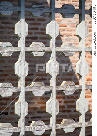 Weathered wooden lattice pattern with brick wall background 139710499