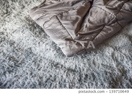 Folded gray blanket on fluffy shag carpet in cozy bedroom interior soft texture warmth comfort home lifestyle details Folded gray blanket on fluffy shag carpet in cozy bedroom interior soft texture warmth comfort home lifestyle details 139710649