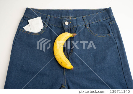 Banana with measuring tape and condom on jean trousers, penis health. 139711340