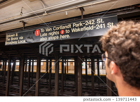 New york, usa august 18,2024. Commuter studying nyc subway sign for uptown and the bronx on the broadway local platform, waiting on the station platform New york, usa august 18,2024. Commuter studying nyc subway sign for uptown and the bronx on the broadway local platform, waiting on the station platform 139711443