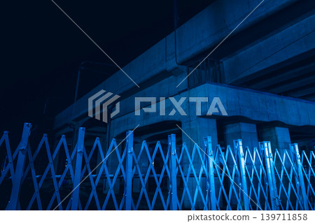 A nighttime view of the concrete underpass and metal retractable gates illuminated by blue light. 139711858