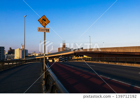 The riverbank and cityscape, illuminated by the refreshing blue sky and sunlight of the morning glow, are adorned with yellow flowers. The riverbank and cityscape, illuminated by the refreshing blue sky and sunlight of the morning glow, are adorned with yellow flowers. 139712192