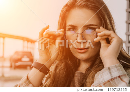 Glasses woman posing young woman holds her frames while looking at the camera during golden hour sunset 139712235