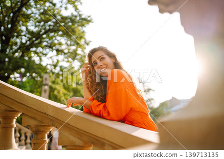 Female tourist in bright dress enjoys sights of the city on sunny day. Concept of lifestyle, fashion Female tourist in bright dress enjoys sights of the city on sunny day. Concept of lifestyle, fashion 139713135