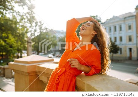 Female tourist in bright dress enjoys sights of the city on sunny day. Concept of lifestyle, fashion Female tourist in bright dress enjoys sights of the city on sunny day. Concept of lifestyle, fashion 139713142