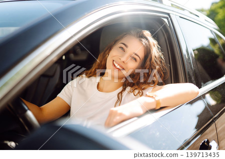 Emotional woman drives a car. The concept of fast movement, traveling by car. Emotional woman drives a car. The concept of fast movement, traveling by car. 139713435