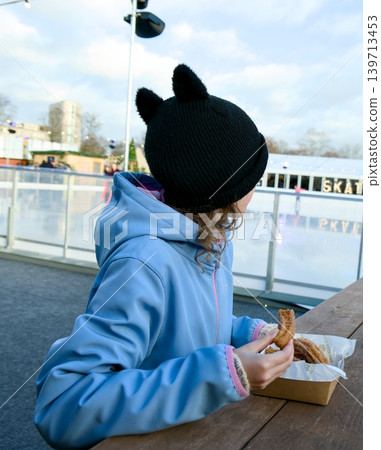 Close-up of a person holding a freshly made churro, dipping it into a small cup of rich chocolate dipping sauce Close-up of a person holding a freshly made churro, dipping it into a small cup of rich chocolate dipping sauce 139713453