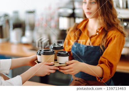 The coffee shop owner gives orders to go. Takeaway drinks concept, small business. The coffee shop owner gives orders to go. Takeaway drinks concept, small business. 139713463