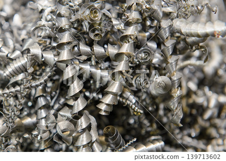 Close-up of a long continuous spiral chip formed during a high-precision steel turning process on a metal lathe. Close-up of a long continuous spiral chip formed during a high-precision steel turning process on a metal lathe. 139713602