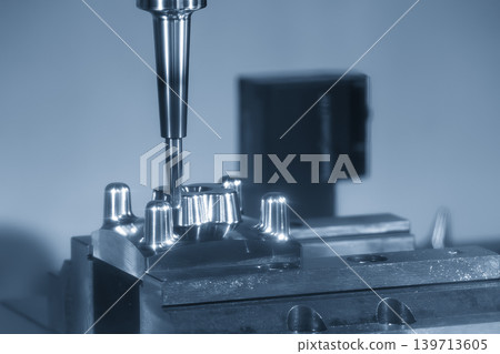 High-precision CNC milling machine cutting complex mold parts using a ball nose end mill tool in a blue-toned scene. High-precision CNC milling machine cutting complex mold parts using a ball nose end mill tool in a blue-toned scene. 139713605