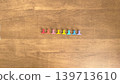 A photo of a wooden table with eight colorful clips lined up. 139713610