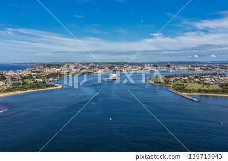 Aerial drone view of a large cargo ship being escorted by tug boats through Newcastle Harbour in New South Wales, Australia. Aerial drone view of a large cargo ship being escorted by tug boats through Newcastle Harbour in New South Wales, Australia. 139713943