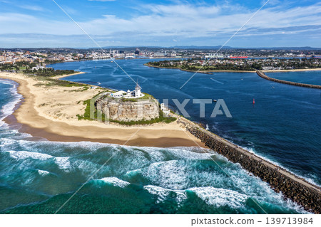 Aerial drone view of Nobbys Lighthouse and sandy Nobbys Beach with Newcastle city skyline and working harbour in the background. Aerial drone view of Nobbys Lighthouse and sandy Nobbys Beach with Newcastle city skyline and working harbour in the background. 139713984
