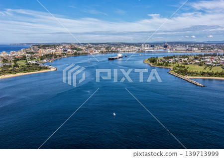 Aerial drone view of a large cargo ship being escorted by tug boats through Newcastle Harbour in New South Wales, Australia. Aerial drone view of a large cargo ship being escorted by tug boats through Newcastle Harbour in New South Wales, Australia. 139713999