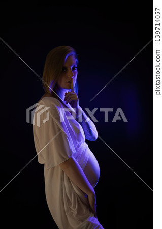 Posing young pregnant woman illuminated by blue fluorescent. Posing young pregnant woman illuminated by blue fluorescent. 139714057