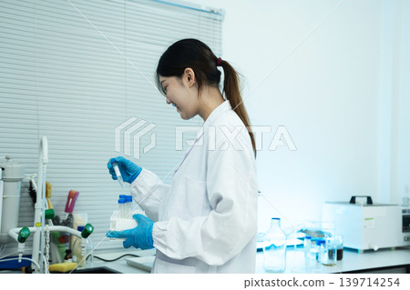 Asian female environmental scientists analyzing water quality samples with centrifuge and petri dish in laboratory. Asian female environmental scientists analyzing water quality samples with centrifuge and petri dish in laboratory. 139714254