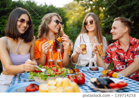 Happy friends in picnic in park. Friends grill meat, have fun, relax. ?oncept of holidays, weekends. Happy friends in picnic in park. Friends grill meat, have fun, relax. ?oncept of holidays, weekends. 139714258