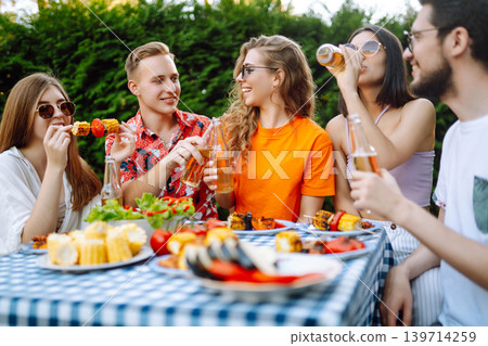 Happy friends in picnic in park. Friends grill meat, have fun, relax. ?oncept of holidays, weekends. Happy friends in picnic in park. Friends grill meat, have fun, relax. ?oncept of holidays, weekends. 139714259