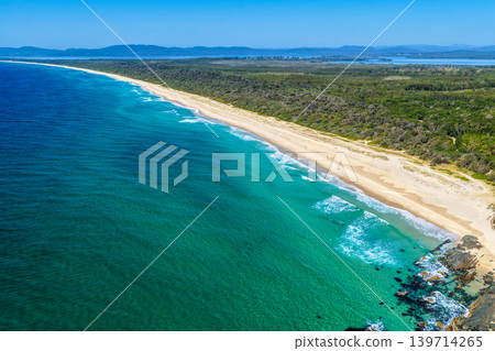 Aerial view of Seven Mile Beach in Forster NSW Australia. Drone photograph captures the expansive sandy shoreline, rolling ocean waves and scenic coastal landscape Aerial view of Seven Mile Beach in Forster NSW Australia. Drone photograph captures the expansive sandy shoreline, rolling ocean waves and scenic coastal landscape 139714265