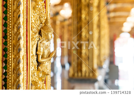 Mythical protector figures across temple wall gilded high relief gold surfaces mirrored details carved borders Thai sacred design reverence grandeur. Mythical protector figures across temple wall gilded high relief gold surfaces mirrored details carved borders Thai sacred design reverence grandeur. 139714328