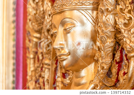 Mythical protector figures across temple wall gilded high relief gold surfaces mirrored details carved borders Thai sacred design reverence grandeur. Mythical protector figures across temple wall gilded high relief gold surfaces mirrored details carved borders Thai sacred design reverence grandeur. 139714332