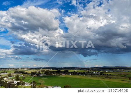 Aerial drone view of rural farmland in Maitland, New South Wales, Australia showing agricultural fields beneath cloudy blue sky. Scenic countryside landscape featuring farming land patterns in the Aerial drone view of rural farmland in Maitland, New South Wales, Australia showing agricultural fields beneath cloudy blue sky. Scenic countryside landscape featuring farming land patterns in the 139714498
