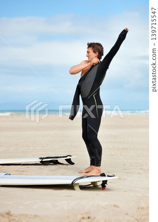 Surfer, man and getting ready with surfboard by ocean with wetsuit, blue sky and dressing with mock up space. Extreme sports, athlete and person on beach for training, surfing workout and adventure Surfer, man and getting ready with surfboard by ocean with wetsuit, blue sky and dressing with mock up space. Extreme sports, athlete and person on beach for training, surfing workout and adventure 139715547