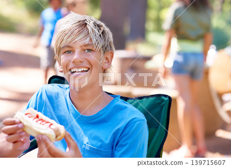 Eating, hotdog and portrait of kid outdoor in camping chair and relax at barbecue with lunch. Happy, child and hungry for food from bbq in park, woods or forest on holiday or vacation in summer Eating, hotdog and portrait of kid outdoor in camping chair and relax at barbecue with lunch. Happy, child and hungry for food from bbq in park, woods or forest on holiday or vacation in summer 139715607