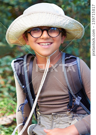 Boy, kid and hiking in nature, portrait with glasses and scout outdoor for adventure, travel and fun with backpack. Discover, exploring and summer camp with happy camper in park, youth and recreation 139715817
