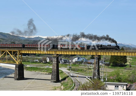 The Ban'etsu Monogatari train crosses the Ichinotogawa Bridge on the Ban'etsu West Line, with the snow-capped Iide Mountain Range in the background. The Ban'etsu Monogatari train crosses the Ichinotogawa Bridge on the Ban'etsu West Line, with the snow-capped Iide Mountain Range in the background. 139716118