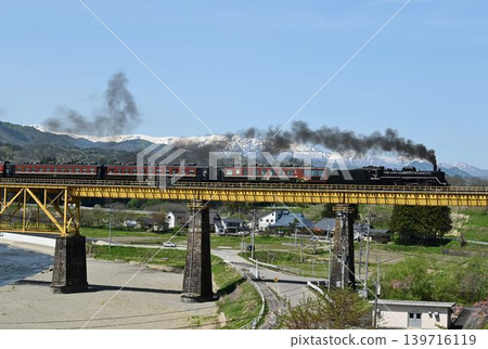 The Ban'etsu Monogatari train crosses the Ichinotogawa Bridge on the Ban'etsu West Line, with the snow-capped Iide Mountain Range in the background. The Ban'etsu Monogatari train crosses the Ichinotogawa Bridge on the Ban'etsu West Line, with the snow-capped Iide Mountain Range in the background. 139716119