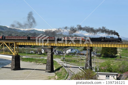 The Ban'etsu Monogatari train crosses the Ichinotogawa Bridge on the Ban'etsu West Line, with the snow-capped Iide Mountain Range in the background. The Ban'etsu Monogatari train crosses the Ichinotogawa Bridge on the Ban'etsu West Line, with the snow-capped Iide Mountain Range in the background. 139716121