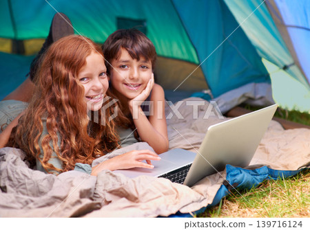 Children, portrait and happy with laptop in tent for camping, social media or online movie with vacation in nature. Family, face and siblings or smile outdoor on grass for trip, relax and holiday fun 139716124