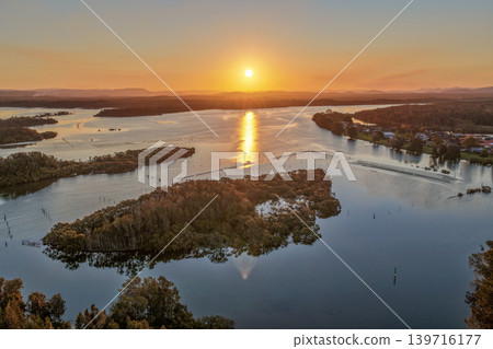 Aerial view of sunset over Wallis Lake in Forster NSW Australia. Drone photograph captures calm waterways, colourful evening sky reflections and the scenic coastal landscape 139716177