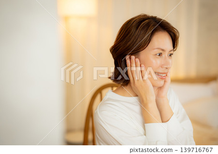 A woman who worries about the condition of her skin in her bedroom at night. A woman who worries about the condition of her skin in her bedroom at night. 139716767