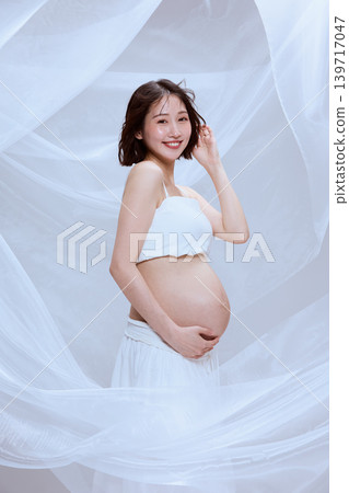 A pregnant woman wrapped in white cloth; a peaceful image of maternity. 139717047