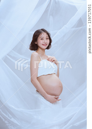 一位孕婦裹著白布,展現了寧靜祥和的孕育景象。 一位孕婦裹著白布,展現了寧靜祥和的孕育景象。 139717051