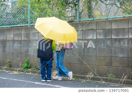 Elementary school student holding an umbrella Elementary school student holding an umbrella 139717091