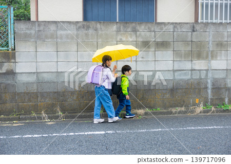 Elementary school student holding an umbrella Elementary school student holding an umbrella 139717096