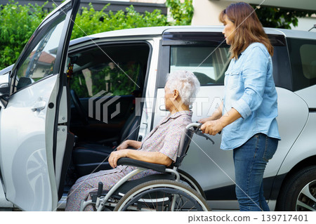 Caregiver help Asian elderly woman disability patient use wheelchair to get in car. Caregiver help Asian elderly woman disability patient use wheelchair to get in car. 139717401