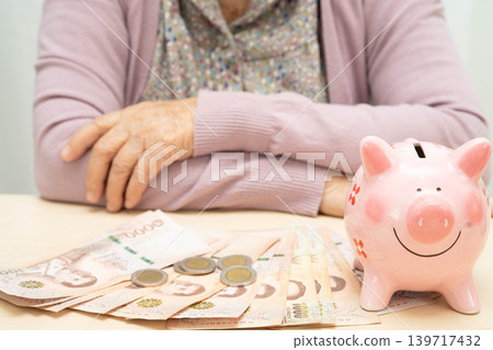 Retired elderly woman counting coins money with piggy bank and worry about monthly expenses and treatment fee payment. 139717432