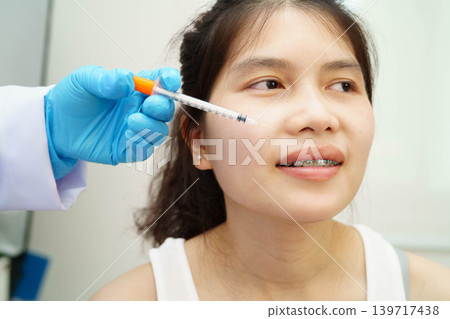Asian woman receiving lip contouring procedure augmentation performed on face. Asian woman receiving lip contouring procedure augmentation performed on face. 139717438