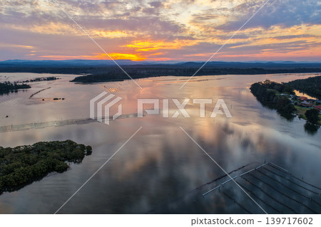 Aerial view of sunset over islands and the Coolongolook River in Tuncurry NSW Australia. Drone photograph captures calm waterways, estuary islands and colourful evening reflections 139717602
