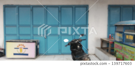Blurry photo of a chicken noodle stall and food cart in front of a minimalist blue shophouse. 139717603