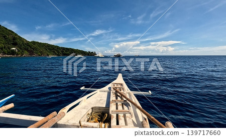 Front view from an outrigger boat heading towards Apo Island in the distant sea horizon. Dauin, Philippines Front view from an outrigger boat heading towards Apo Island in the distant sea horizon. Dauin, Philippines 139717660