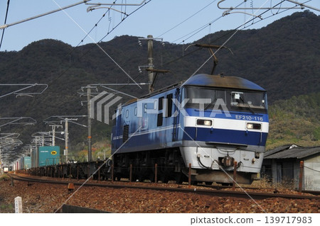 一列由EF210型機車牽引的貨運列車正在山陽本線上行駛。 一列由EF210型機車牽引的貨運列車正在山陽本線上行駛。 139717983