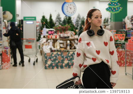 A store sells Christmas decorations. A young girl is choosing decorations for the Christmas celebration. A store sells Christmas decorations. A young girl is choosing decorations for the Christmas celebration. 139719313